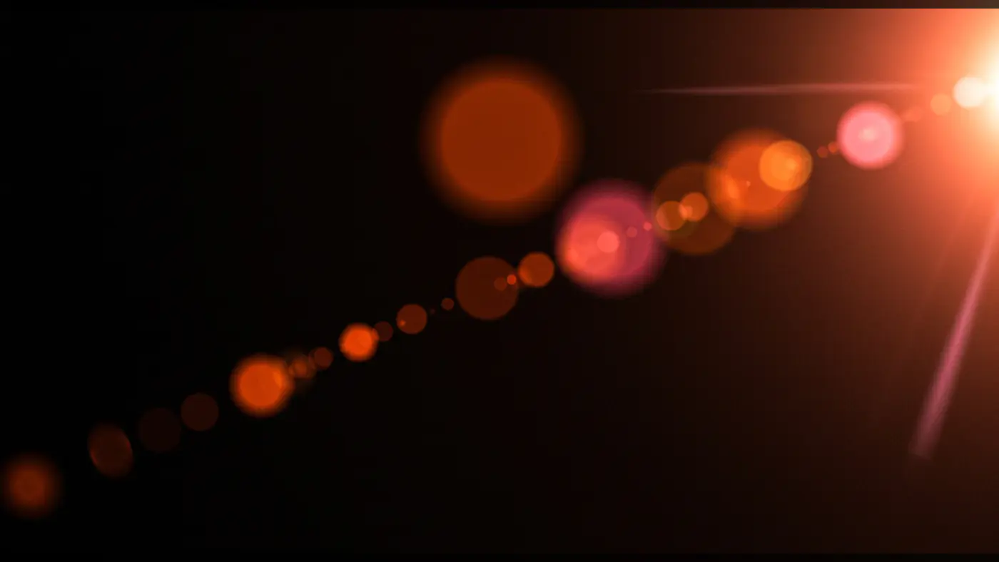 Warm Orange Lens Flare Burst with Circular Bokeh Trail on Black Background