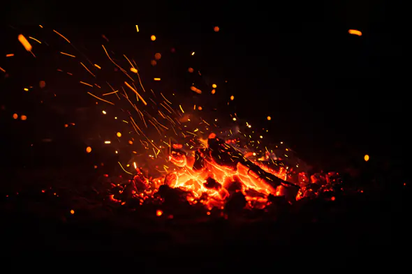 Glowing Charcoal Fire with Flying Orange Sparks Texture Background