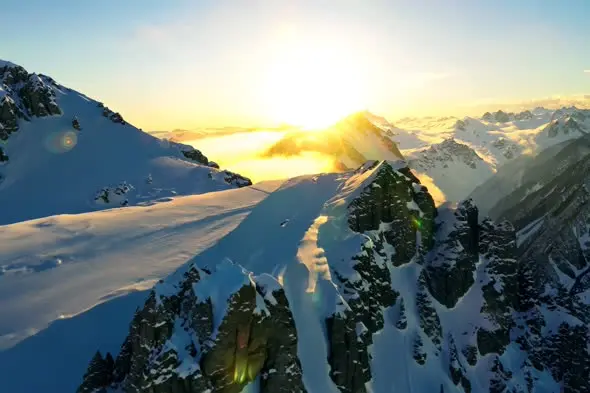 Majestic Sunset Over Snow-Capped Mountain Range Aerial View