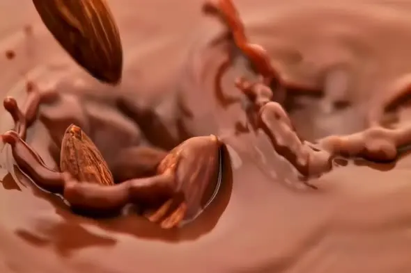 Almonds Falling into Swirling Liquid Chocolate