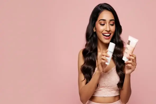 Beauty Model Displaying Skincare Products on Pink Background