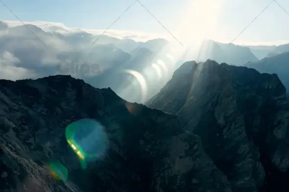 Aerial View of Sunlight Breaking Through Clouds Over Mountain Peaks ...