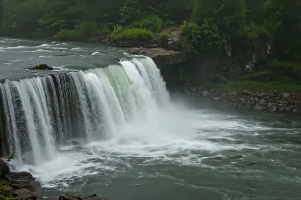 Powerful Waterfall Cascading Into Turbulent River Scenic Landscape