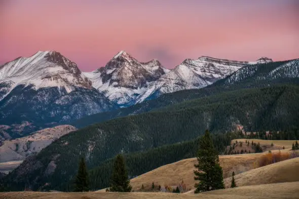 Snowy mountains under pink sunset sky