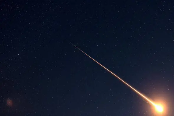 Fiery Meteor Trail Across Starry Night Sky