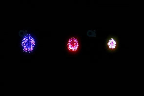 Triple Fireworks Burst in Blue, Red, and Yellow Against Night Sky