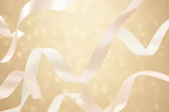 Floating White Satin Ribbons on a Soft Golden Bokeh Background