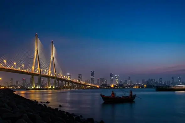 Illuminated Cable Bridge with Traditional Boat at Twilight