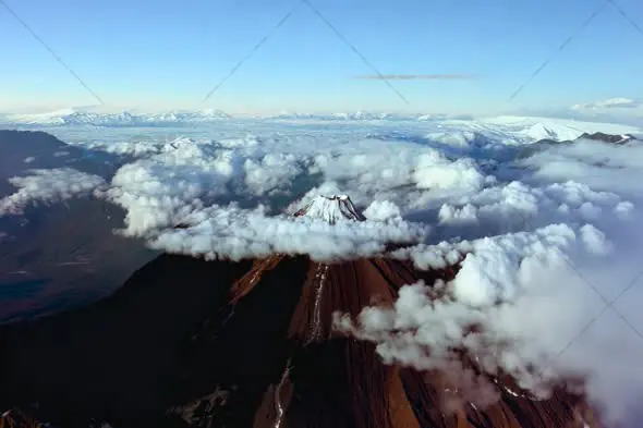 Aerial View of Majestic Snow-Capped Mountains Shrouded in Clouds