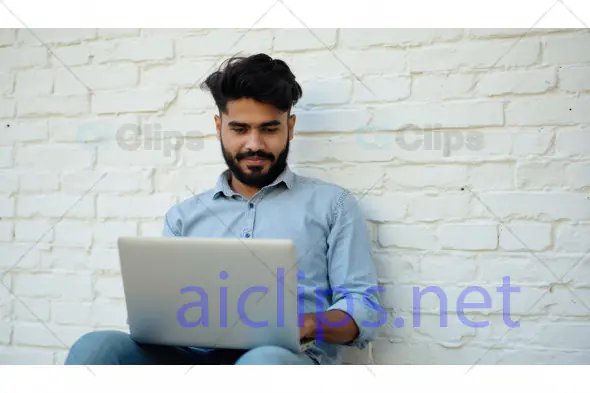 Young Man Working on Laptop Against Brick Wall