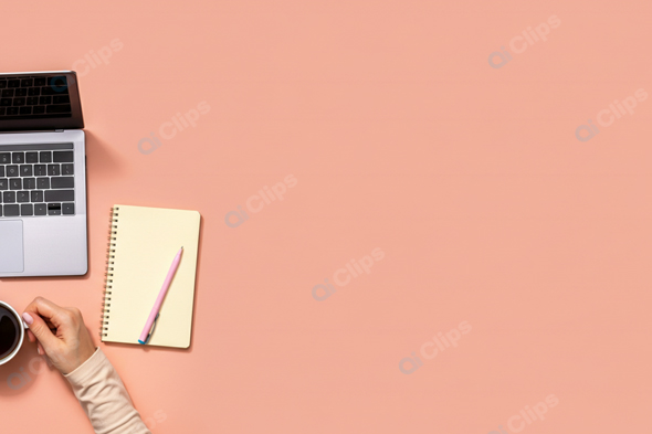 Workspace with Laptop, Notebook, and Coffee Mug on Peach Background